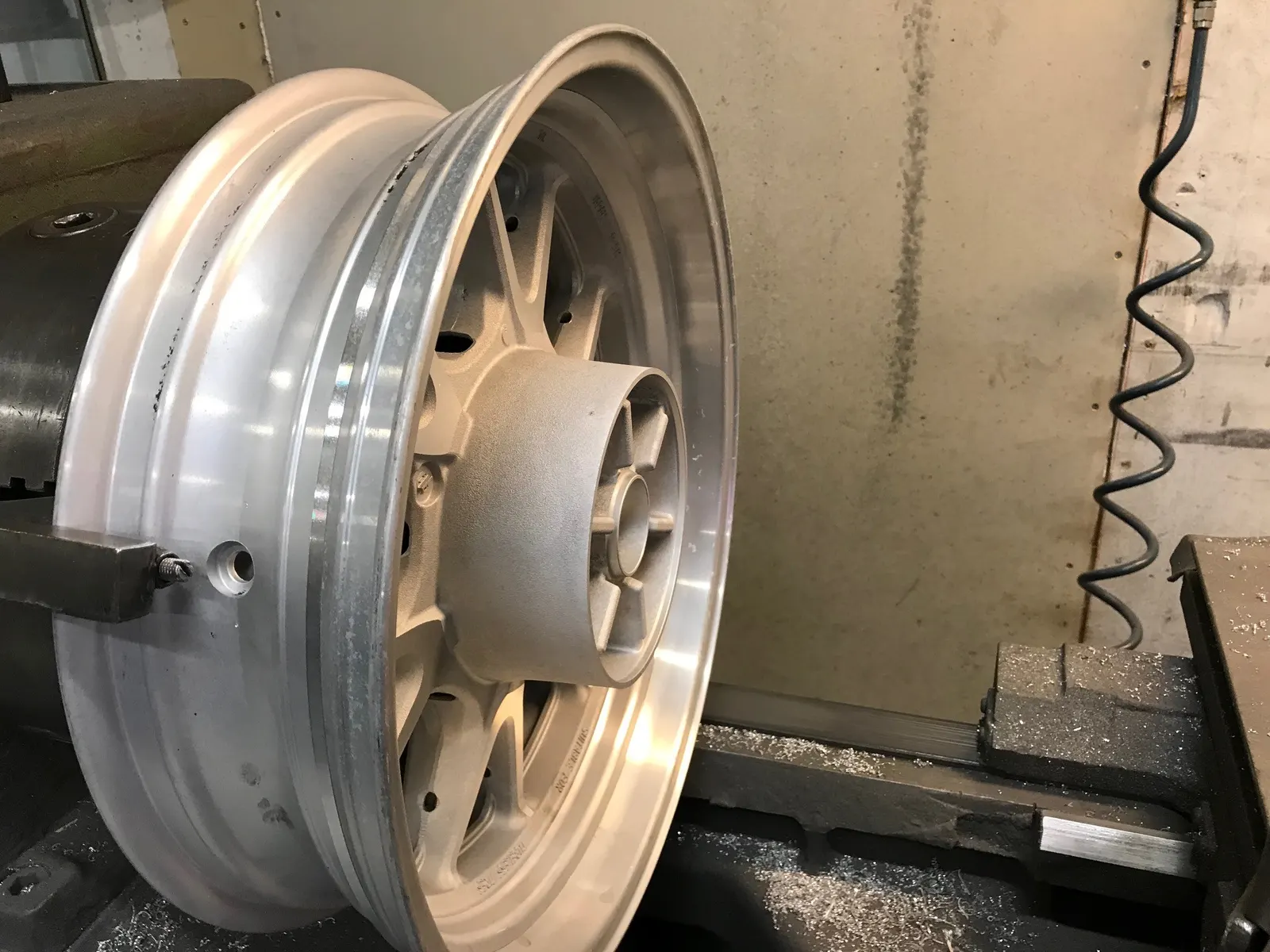 MC-fälg under breddning: rent aluminium efter svetsning, uppspänd i maskin